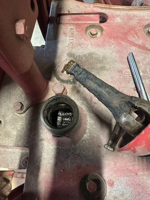 A partially disassembled mechanical component with exposed gears is shown on a red surface.