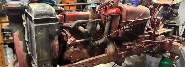 An old, weathered farm tractor is shown in a workshop setting.