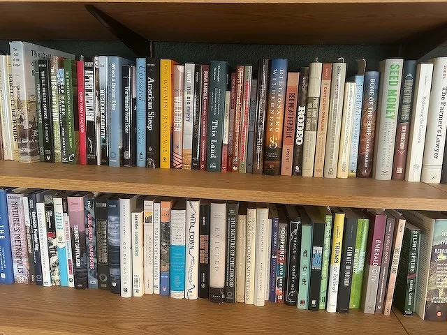 A wooden bookshelf is filled with a diverse collection of books on various topics.